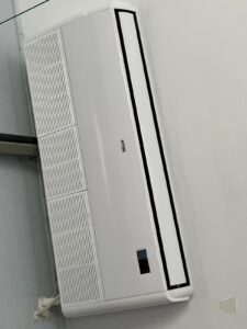 Unidad mural de aire acondicionado instalada en una pared blanca. Moderno y silencioso, permite climatizar el espacio de forma eficiente.