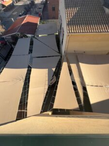 Vista superior del patio exterior del centro con varios toldos beige instalados, que proporcionan sombra y protección solar. La estructura cubre completamente el área peatonal entre los edificios.