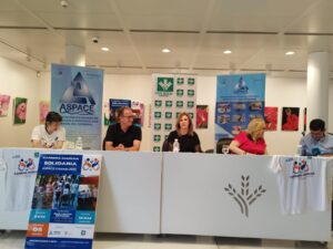 Cinco personas sentadas tras una mesa blanca durante la rueda de prensa de presentación de la 10ª Carrera-Marcha Solidaria ASPACE Granada 2025. Detrás se ven lonas promocionales de ASPACE y carteles del evento.