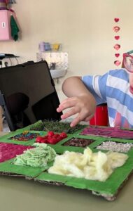 Mujer tocando un panel sensorial con distintos materiales y texturas