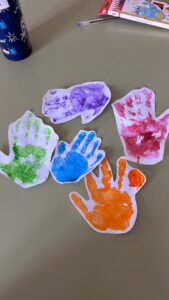 Huellas de manos pintadas con colores sobre recortes de papel blanco